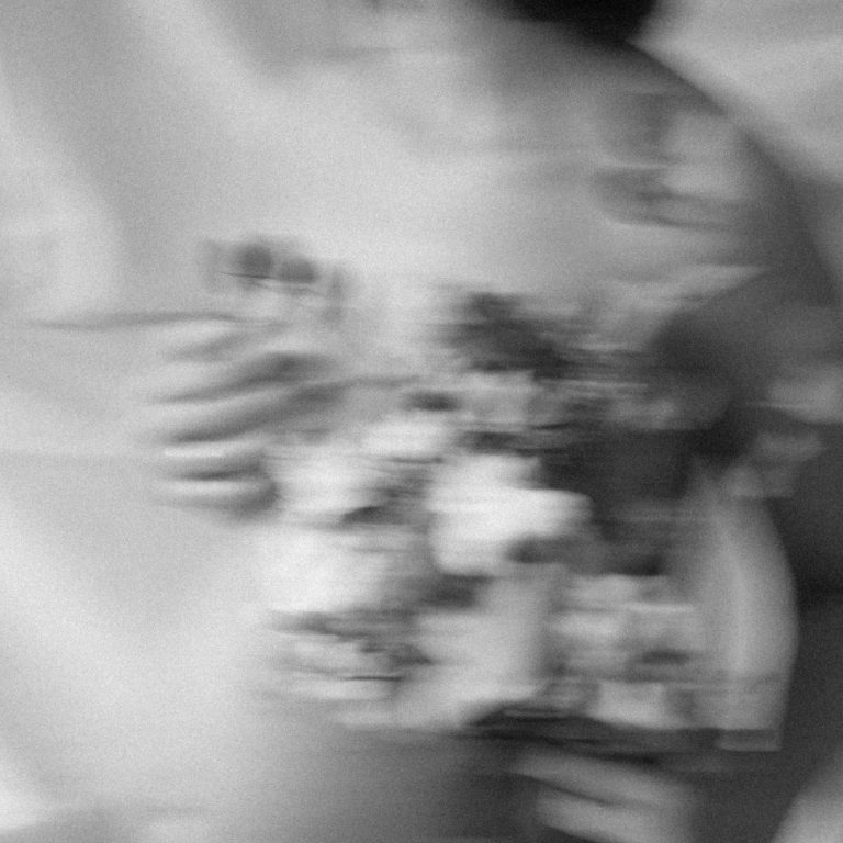 Verschwommenes Bild von Schwangerer Person mit Nacktem Oberkörper und Blumenstrauss.